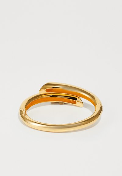 Goldfarbenes Metallarmband mit einem glatten, eleganten Design in überlappender Form, polierter Oberfläche und ohne sichtbare Verzierungen.