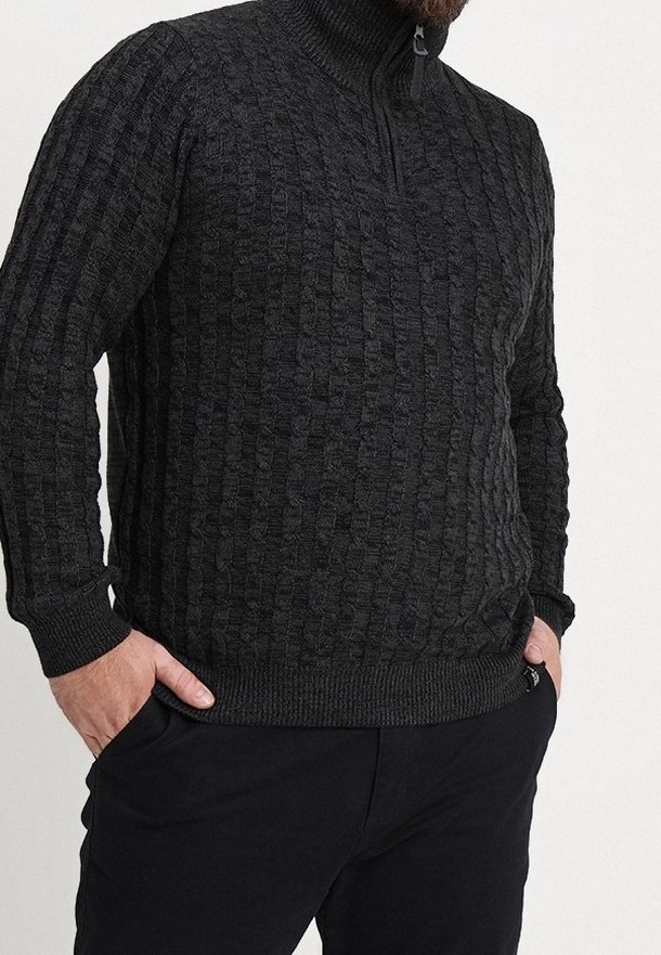Pull en maille gris foncé avec un col haut et une demi-fermeture éclair. Texture côtelée avec un motif en blocs. Manches longues et coupe ajustée.
