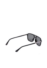Lunettes de soleil rectangulaires noires avec verres foncés et branches fines, présentées en angle sur un fond blanc.