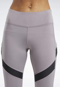 Leggings grigi chiari con vita alta, caratterizzati da strisce diagonali nere e un tessuto liscio ed elastico con cuciture piatte.