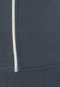 Tela de punto gris con una textura suave que presenta una costura blanca contrastante en el centro y acentos acanalados en la parte inferior.