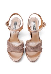 Zapatos de tacón abierto en piel metálica de color oro rosado con correas de textil cruzadas. Cuenta con una correa ajustable en el tobillo y una plantilla lisa y texturizada.