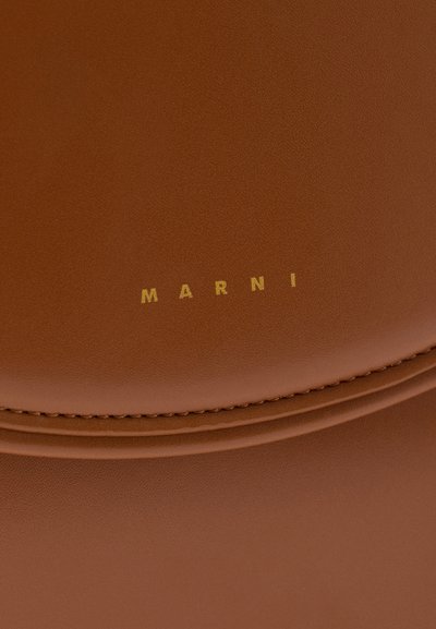 Καφέ δερμάτινη επιφάνεια με λεπτή ραφή και μικρά χρυσά γράμματα "MARNI" στο κέντρο πάνω από μια καμπυλωτή ραφή.