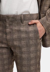 Braun karierte Hose aus strukturiertem Stoff, mit flachem Vorderteil, Seitentaschen und einem oberen Knopfverschluss.