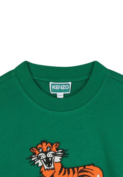 Zielona bluza z ribbowanym kołnierzem, z haftowanym pomarańczowym wzorem tygrysa. Gładka tekstura i luźny krój. Widoczna metka marki.