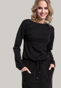 Black long-sleeve dress with a round neckline, side pockets, and drawstring waist. Features accent stitching along the shoulders.