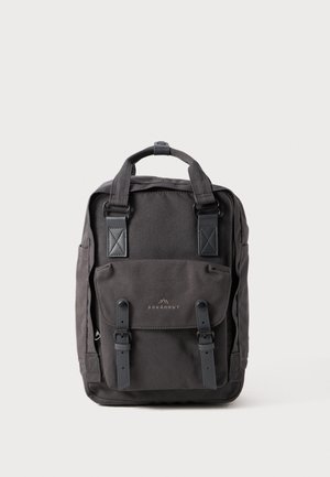 Black canvas backpack with reinforced corners, a front flap pocket, two adjustable straps, and a top handle for carrying.