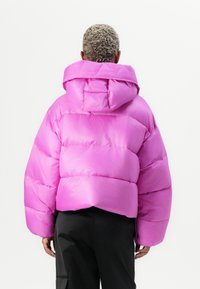 Fuksia pufferjakke med en kort silhuett, stor hette og quiltet tekstur. Har et glatt, skinnende stoff og senkede skuldre.