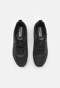 Černé sportovní boty Skechers s síťovinovým svrškem, šněrováním, bílou mezipodešví a polstrovaným límcem. Na jazyku je logo.