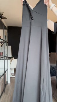 Fekete maxi ruha V-nyakkivágással, redőzött szoknyával és sima textúrával. Az anyag könnyűnek és folyékonynak tűnik, alkalmas különböző eseményekre.