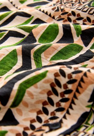 Tissu présentant un motif avec des feuilles vertes, des accents noirs et un fond beige. La texture semble douce et légèrement froissée.