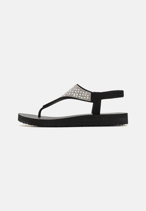 Black flip-flop sandal featuring a textured strap with silver accents, a cushioned black sole, and a durable rubber construction.