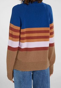 Neulottu neulepaita korkealla kaula-aukkolla, jossa on sinisiä, ruskeita, vaaleanpunaisia ja viininpunaisia vaakaraitoja. Resoritetut hihansuut ja helma.