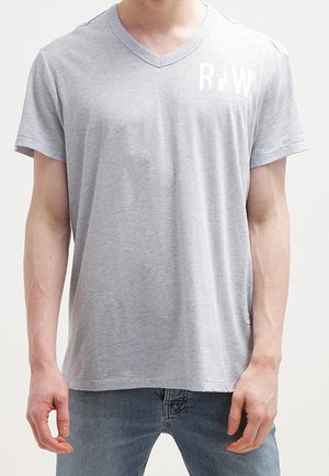 Graues T-Shirt mit kurzen Ärmeln und V-Ausschnitt aus weichem Stoff, mit einem weißen aufgedruckten Logo auf der linken Brust. Lässige Passform.