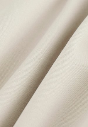 Nærbillede af glat, beige stof med bløde folder, der viser fin vævet struktur og subtil diagonal ribning.