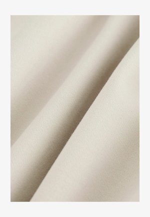Close-up of smooth, beige fabric with soft folds showing fine woven texture and subtle diagonal ribbing.