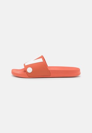 Coral slide sandal with a wide upper strap featuring a white accent. Smooth plastic material and flat sole. Lightweight design for easy wear.