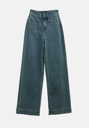 Bredde ben denim bukser i falmet blå, med høy midje, to frontlommer og klassisk knappelukking. Stoffet har en myk og glatt tekstur.