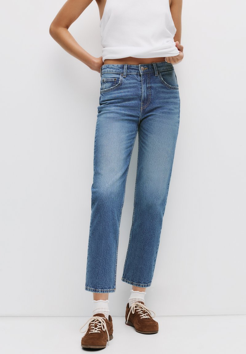 Ljusblå denimjeans med rak passform, blekt mönster, femfickdesign och sömnadsdetaljer. Bärs med bruna mockaskor.