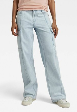 Lichtblauwe cargobroek met een losse fit, gemaakt van denim. Voorzien van zijzakken en contrasterende stiksels. Gecombineerd met lichte schoenen.
