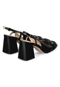 Sandalias de tacón de cuero negro con un amplio tacón cuadrado, diseño de punta abierta, correa al tobillo y acentos decorativos de cadena de metal.