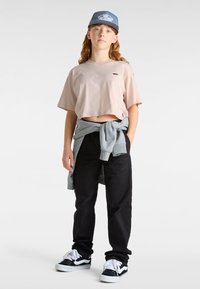 Rosa kortärmad t-shirt, svarta byxor, grå sweatshirt knuten i midjan och svart-vita sneakers. Basebollkeps med blå accenter.