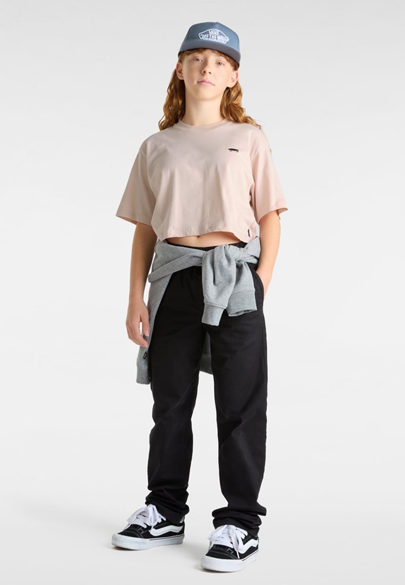 Rosa kortärmad t-shirt, svarta byxor, grå sweatshirt knuten i midjan och svart-vita sneakers. Basebollkeps med blå accenter.