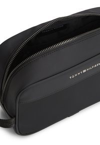 Μαύρο ορθογώνιο νεσεσέρ με ασημί φερμουάρ, μπροστινή τσέπη και λογότυπο Tommy Hilfiger στην πρόσοψη και στο εσωτερικό φόδρα.