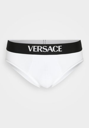 Caleçons en coton blanc avec une taille noire affichant "VERSACE" en lettres blanches. Présente un design ajusté et une texture lisse.
