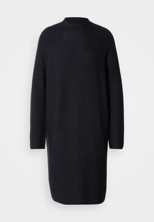 Rochie neagră tricotată cu mâneci lungi și guler înalt. Are o croială lejeră și o lungime care ajunge puțin deasupra genunchiului. Textură moale.