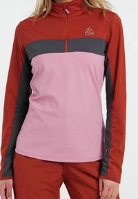 Rotes Langarmoberteil mit rosa und grauen Paneelen, Halbreißverschluss am Kragen und Logodetail auf der Brust. Glatte Textur, die für Sportbekleidung ausgelegt ist.