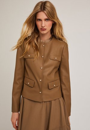 Chaqueta de cuero marrón con cuello, botones a presión y dos bolsillos frontales. Acabado texturizado y diseño ajustado, combinada con un vestido a juego.