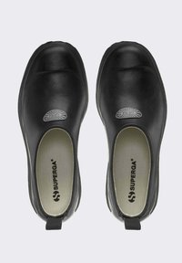 Scarpe slip-on nere con un'esterno in pelle liscia, punta arrotondata e dettagli del logo discreti. Fodera testurizzata, soletta morbida e linguetta.