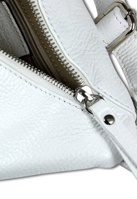 Weiße Lederhandtasche mit strukturiertem Oberflächen, Reißverschluss mit silberner Hardware und abnehmbarem Gurt mit poliertem Akzent.