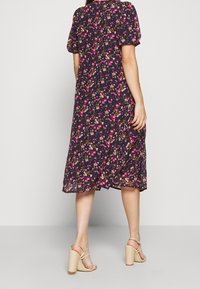 Plynná černá květinová šaty s krátkými nabíranými rukávy, s růžovými a žlutými květy po celé ploše. Nosit s světlými blokovými podpatky.