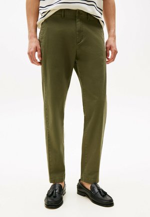 Pantalones verde oliva de corte recto, hechos de tela ligera, con bolsillos delanteros y una textura suave, combinados con mocasines negros.