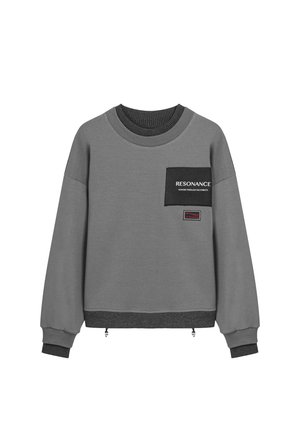 Grijze sweatshirt met een zwarte patchzak, geribbelde halslijn en manchetten, met de tekst "RESONANCE" en een label aan de onderkant. Textuurstof.