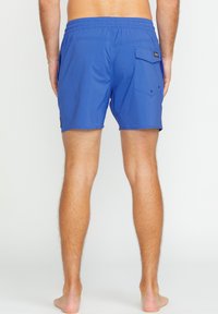 Shorts de bain bleus en tissu léger, dotés d'une poche arrière et d'une taille élastique. Texture lisse avec des coutures renforcées.