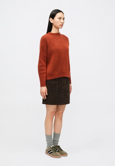 Roostevärvi karvane kampsun, pruuni seemisnahast seelik ees taskutega, hallid sokid ja rohelised tossud mustade triipudega. Lihtne ja vabaaja ansambel.