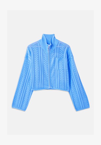 Ανοιχτό μπλε κοντό μπουφάν φτιαγμένο από υφασμάτινη πλέξη, με ψηλό γιακά, πλήρη φερμουάρ και αριστερή τσέπη στο στήθος με οριζόντιες ρίγες.