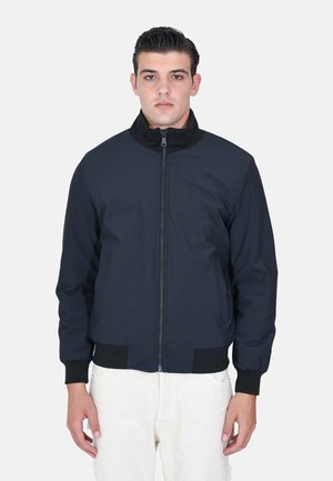 Giacca bomber navy con zip frontale, polsini e colletto a coste. Realizzata in tessuto morbido, con tasche laterali e un design aderente.