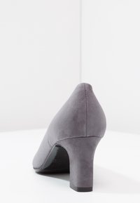 Chaussure à talon haut en daim gris avec un bout rond et un talon bloc de hauteur moyenne. Texture lisse et design épuré sans motifs ni accents visibles.