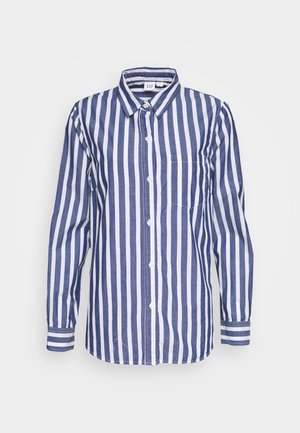 Chemise à boutons rayée avec des rayures verticales alternées bleu marine et blanches, manches longues, col et poche poitrine. Fabriquée en coton.