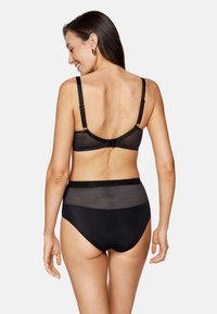 Czarny komplet bielizny składający się z teksturowanego biustonosza z regulowanymi ramiączkami oraz majtek z wysokim stanem, oba zdobione geometrycznym wzorem.