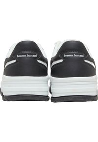 Svartvita sportskor med vadderad krage, strukturerat läderöverdel och en tjock sula med en framträdande varumärkeslogotyp på hälen.