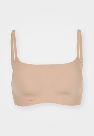 Nude saumaton rintaliivi säädettävillä olkaimilla, sileällä pinnalla ja yksinkertaisella muotoilulla. Ei sisäpuolta tai pehmustetta mukavuuden ja monikäyttöisyyden vuoksi.