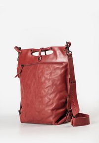 Rode leren tas met een gestructureerd oppervlak, ruime compartimenten en een verstelbare schouderband. Voorzien van een unieke uitsparing in de handgreep en ritsdetails.