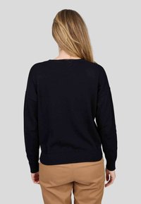 Pull noir en tricot à coupe décontractée, à manches longues et avec un ourlet côtelé. Texture lisse, design simple et style col rond.