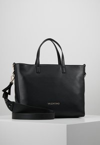 Svart läderväska med dubbla handtag och en avtagbar axelrem. Har en slät yta och en guldfärgad "Valentino"-logotyp på framsidan.