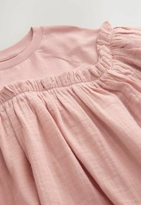 Helles rosa Kleid mit einem gerafften Design und Rüschenausschnitt. Weicher, strukturierter Stoff mit fließender Silhouette und Falten an der Taille.
